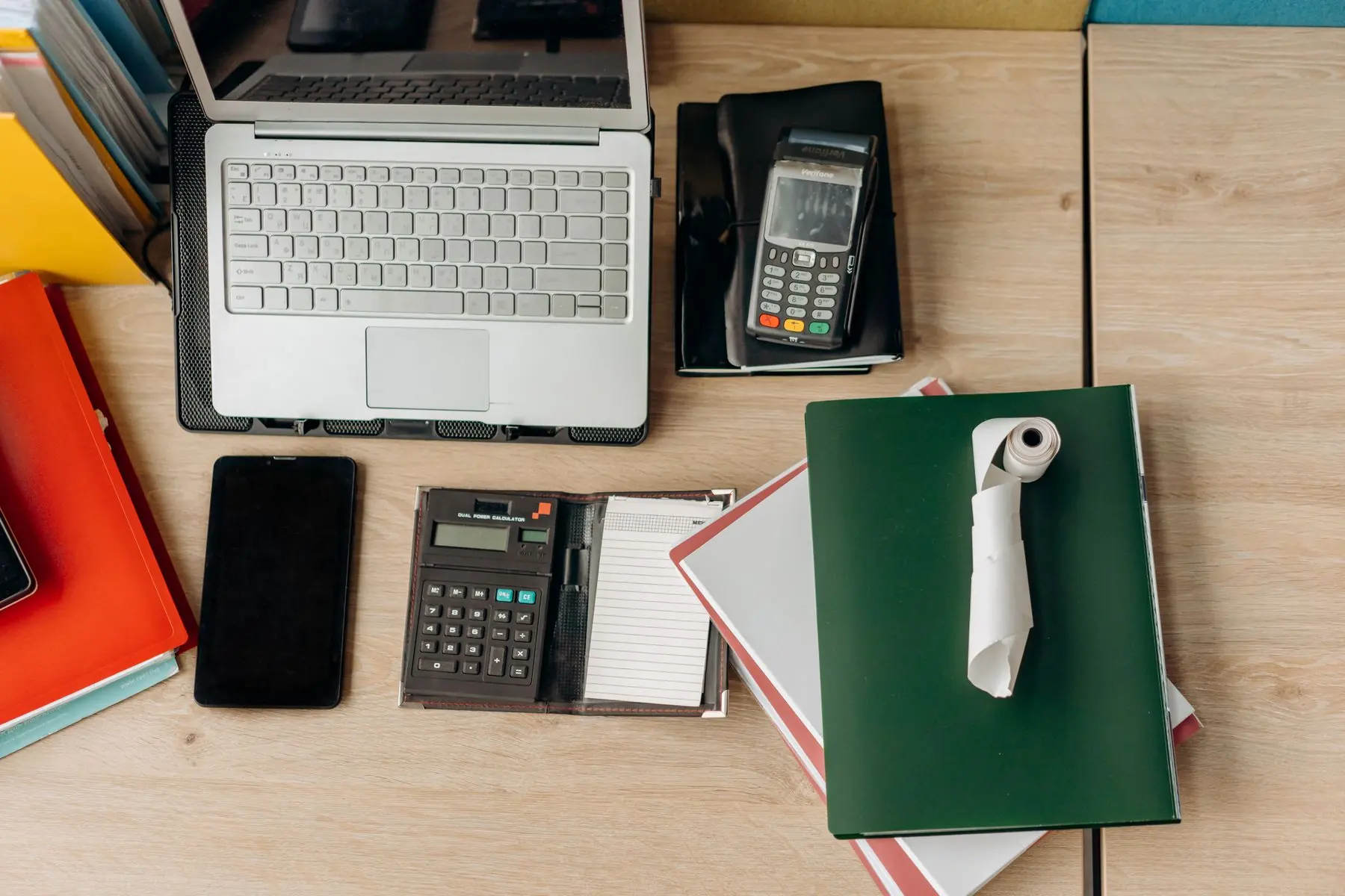 Bovenaanzicht van een bureau met laptop, rekenmachine en mappen