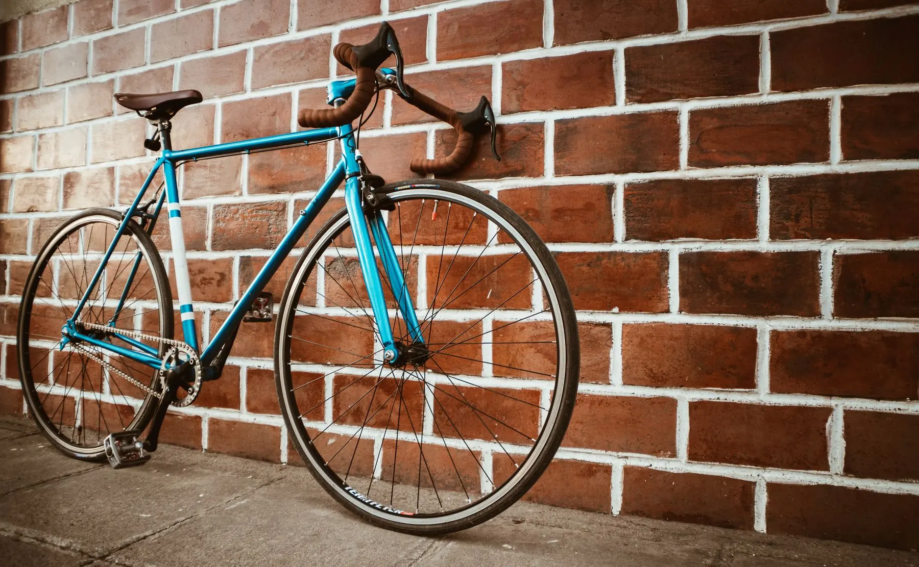 Blauwe racefiets tegen een bakstenen muur